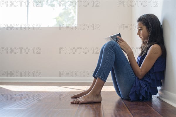 Mixed race girl using digital tablet in empty room