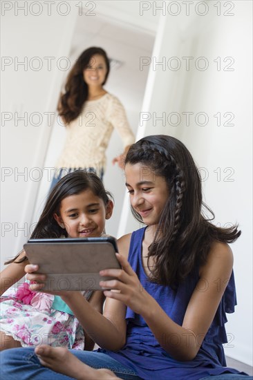 Mother watching daughters use digital tablet