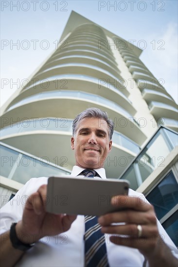 Low angle view of Caucasian businessman using cell phone at high rise building