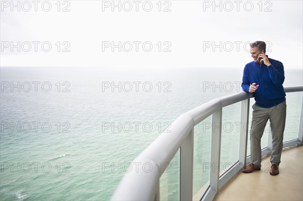 Caucasian businessman talking on cell phone on balcony