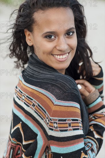 Mixed race woman wearing stylish sweater on beach