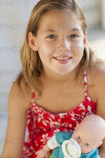 Close up of Caucasian girl holding baby doll