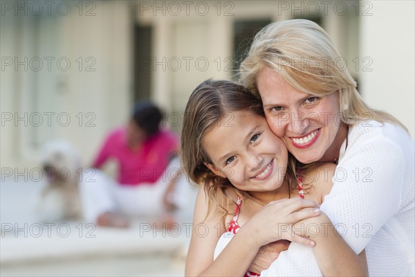 Smiling mother and daughter hugging outdoors