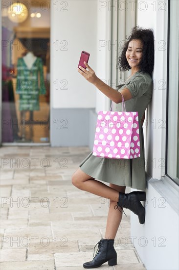 Black woman taking selfie outside store