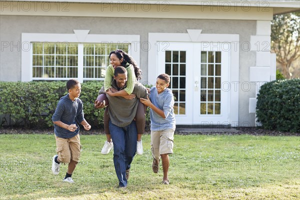 Family playing football in backyard