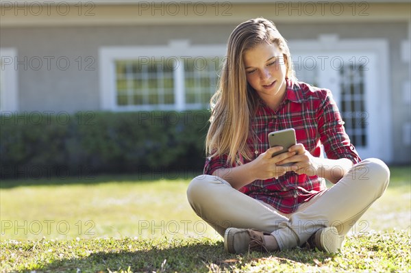 Caucasian girl using cell phone in backyard