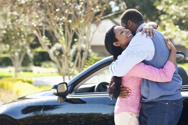 Couple hugging near convertible