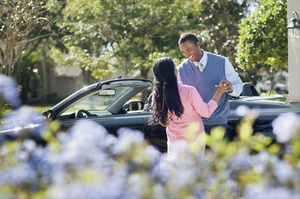 Couple hugging near convertible