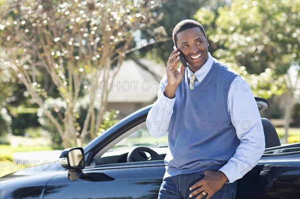 Black man talking on cell phone at convertible