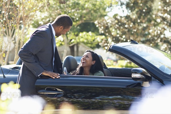 Gentleman opening door of convertible for woman