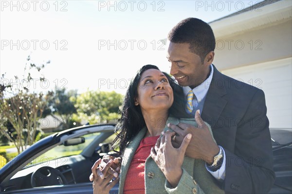 Couple hugging near convertible