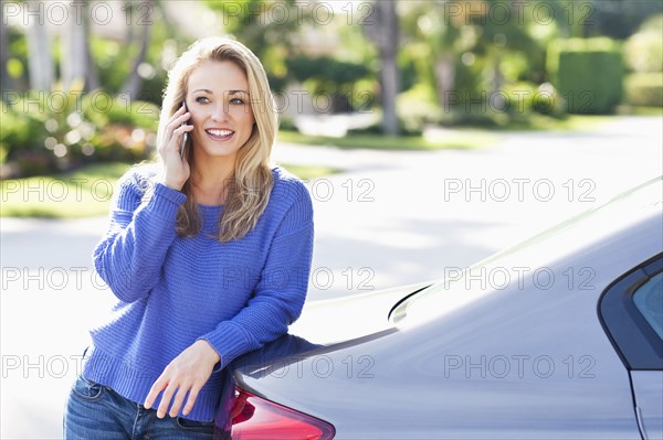 Caucasian woman talking on cell phone at car