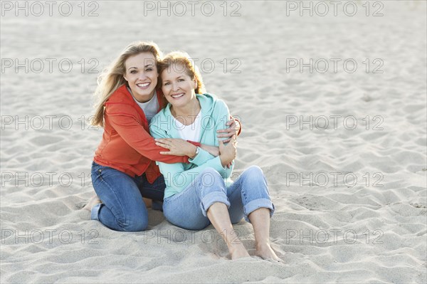 Caucasian mother and daughter hugging on beach