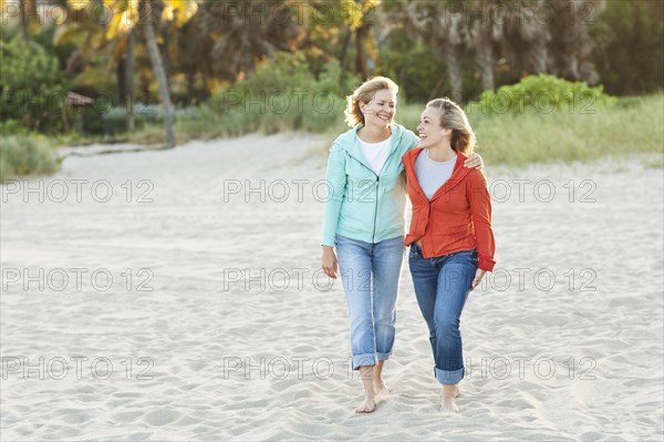 Caucasian mother and daughter walking on beach