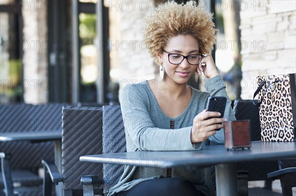 Black woman using cell phone at cafe