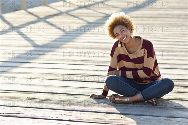 Black woman sitting on wooden boardwalk