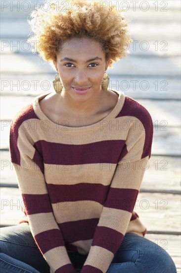 Black woman sitting on wooden boardwalk