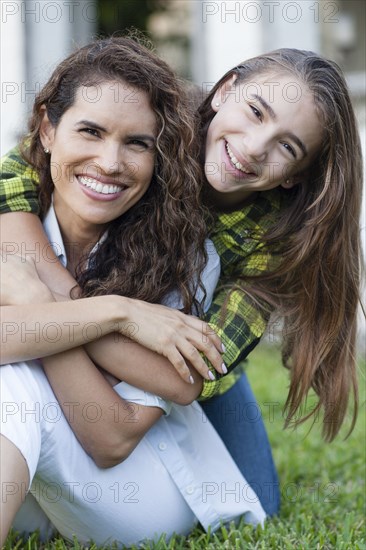 Hispanic mother and daughter hugging in backyard