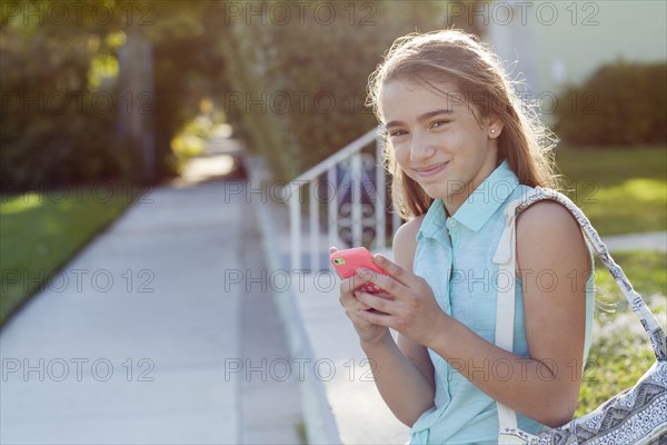 Hispanic girl using cell phone on sidewalk