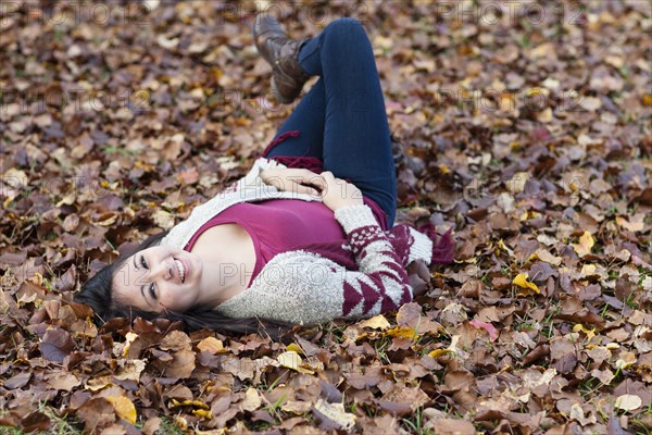 Hispanic teenage girl laying in autumn leaves