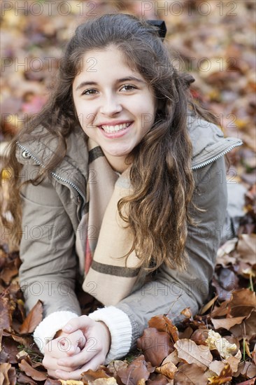 Hispanic girl laying in autumn leaves