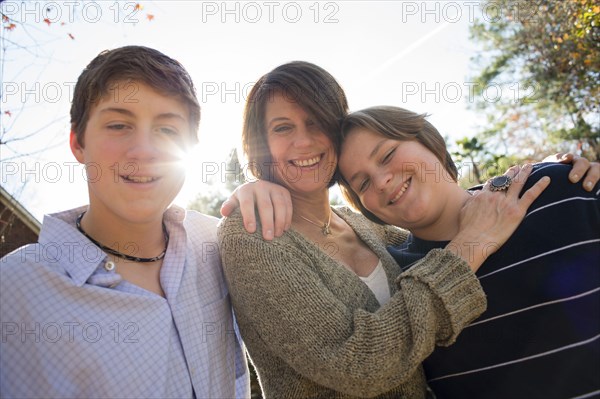 Caucasian mother and sons hugging outdoors