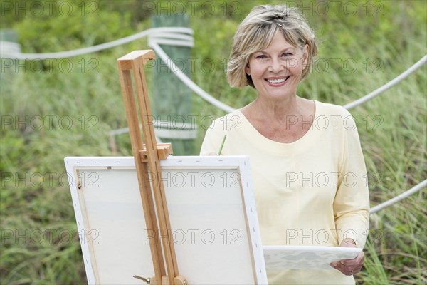 Older Caucasian woman painting outdoors