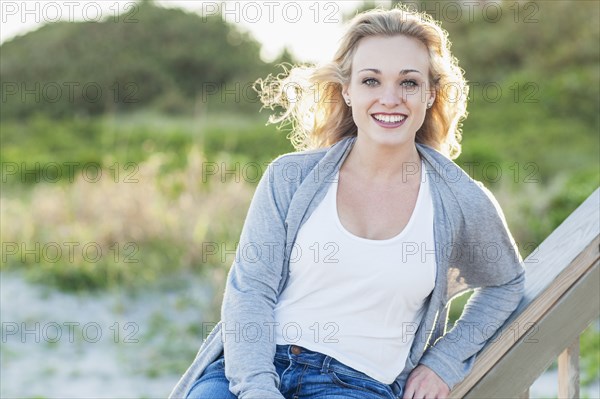 Smiling Caucasian woman sitting on banister over beach