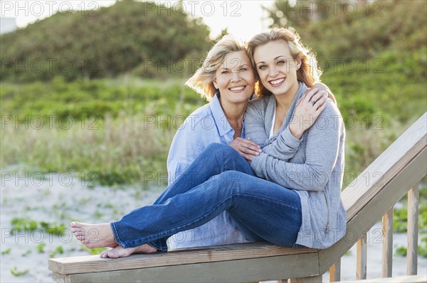Caucasian mother and daughter hugging on beach