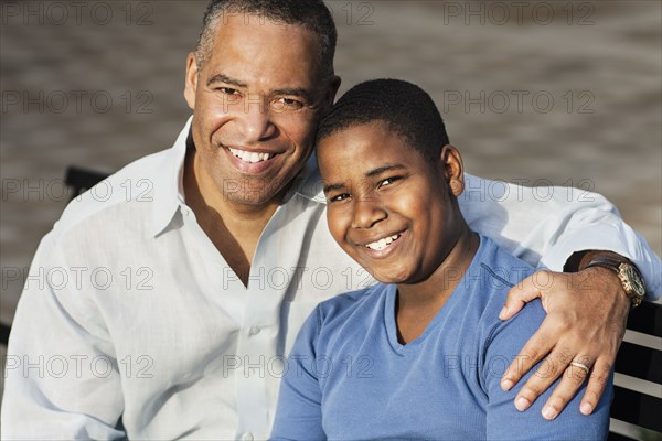 African American father and son hugging on bench