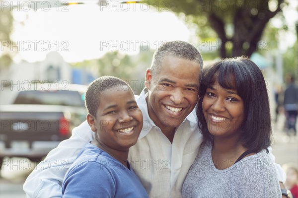 African American father and children hugging in city