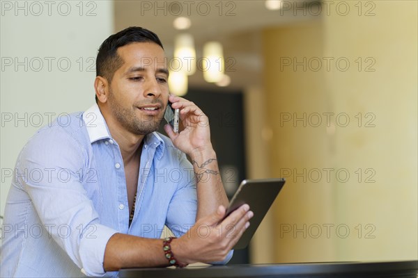 Hispanic man using digital tablet and cell phone