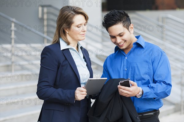 Business people using technology near staircase