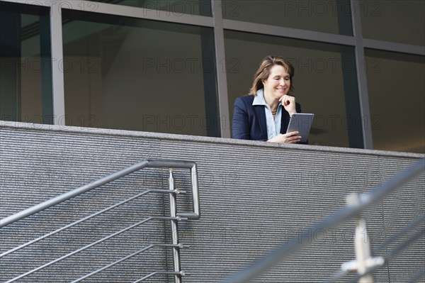 Caucasian businesswoman using digital tablet on balcony