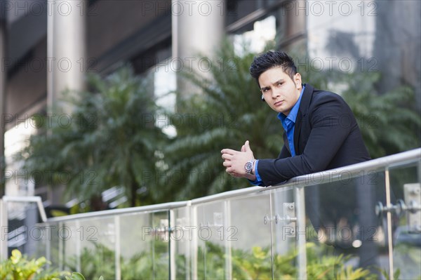 Mixed race businessman leaning on banister