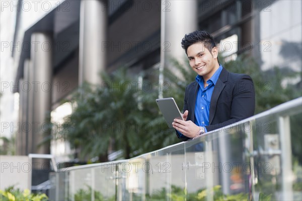 Mixed race businessman using digital tablet outdoors