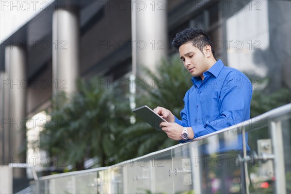 Mixed race businessman using digital tablet outdoors