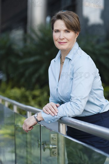 Caucasian businesswoman leaning on banister outdoors