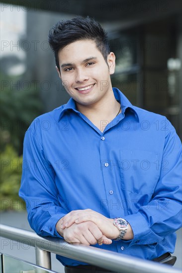 Mixed race businessman leaning on banister outdoors