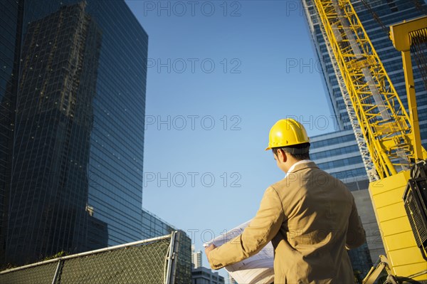 Mixed race architect reading blueprints at construction site