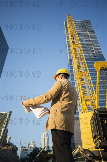 Mixed race architect reading blueprints at construction site