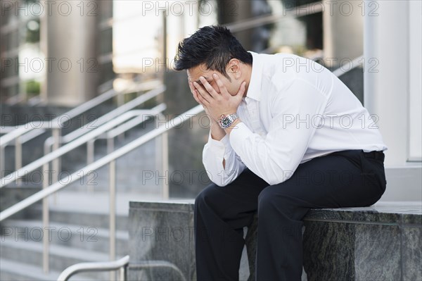 Stressed mixed race businessman covering his face