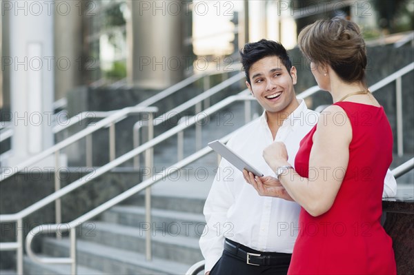 Business people using digital tablet near staircase