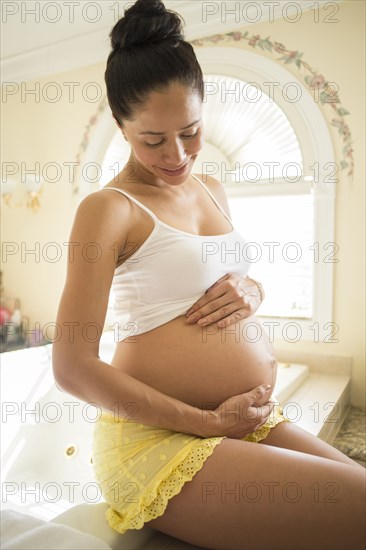 Pregnant Hispanic woman holding her belly