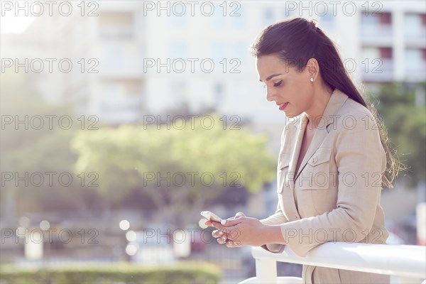 Hispanic businesswoman using cell phone outdoors