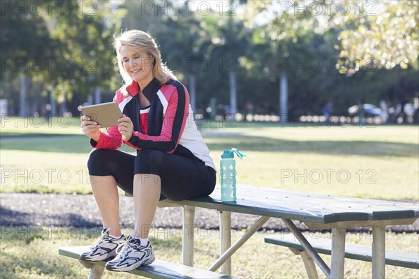 Caucasian woman using digital tablet in park