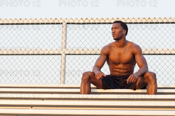 Serious Black athlete siting on bleachers