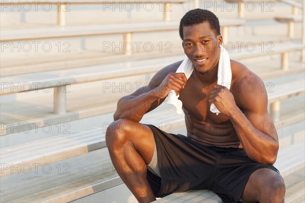 Black athlete sitting on bleachers