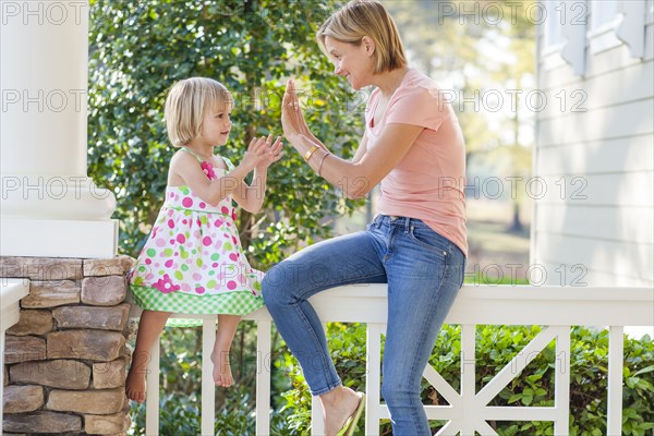 Caucasian mother and daughter playing on patio