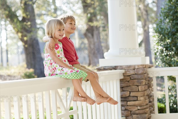 Caucasian brother and sister hugging on patio